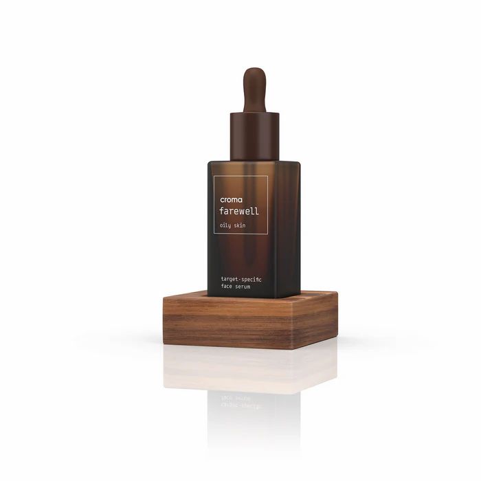 Braune Serumflasche mit Pipette auf Holzsockel. Aufschrift: Croma Farewell Oily Skin. Target-specific Face Serum.