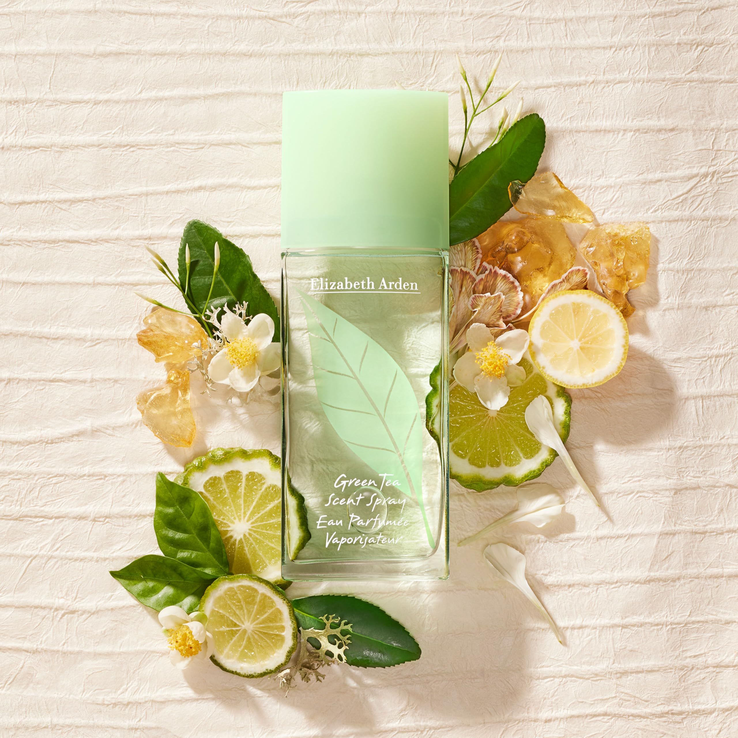 Flakon umgeben von Zitronen, Bergamotte, Blättern und Blüten. Aufschrift: Elizabeth Arden, Green Tea Scent Spray, Eau Parfumée Vaporisateur.
