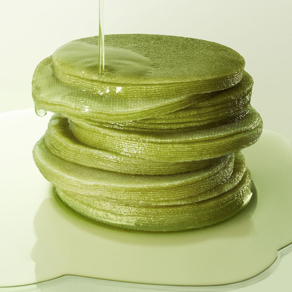 Gestapelte grüne Matcha Tea Pads, die mit Flüssigkeit übergossen werden.