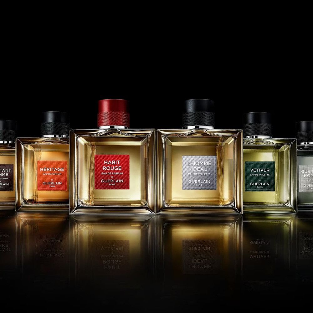 Reihe von Parfümflakons. Quadratische Glasflakons mit farbigen Etiketten und Verschlüssen. Habit Rouge-Flakon mit rotem Etikett und Verschluss.