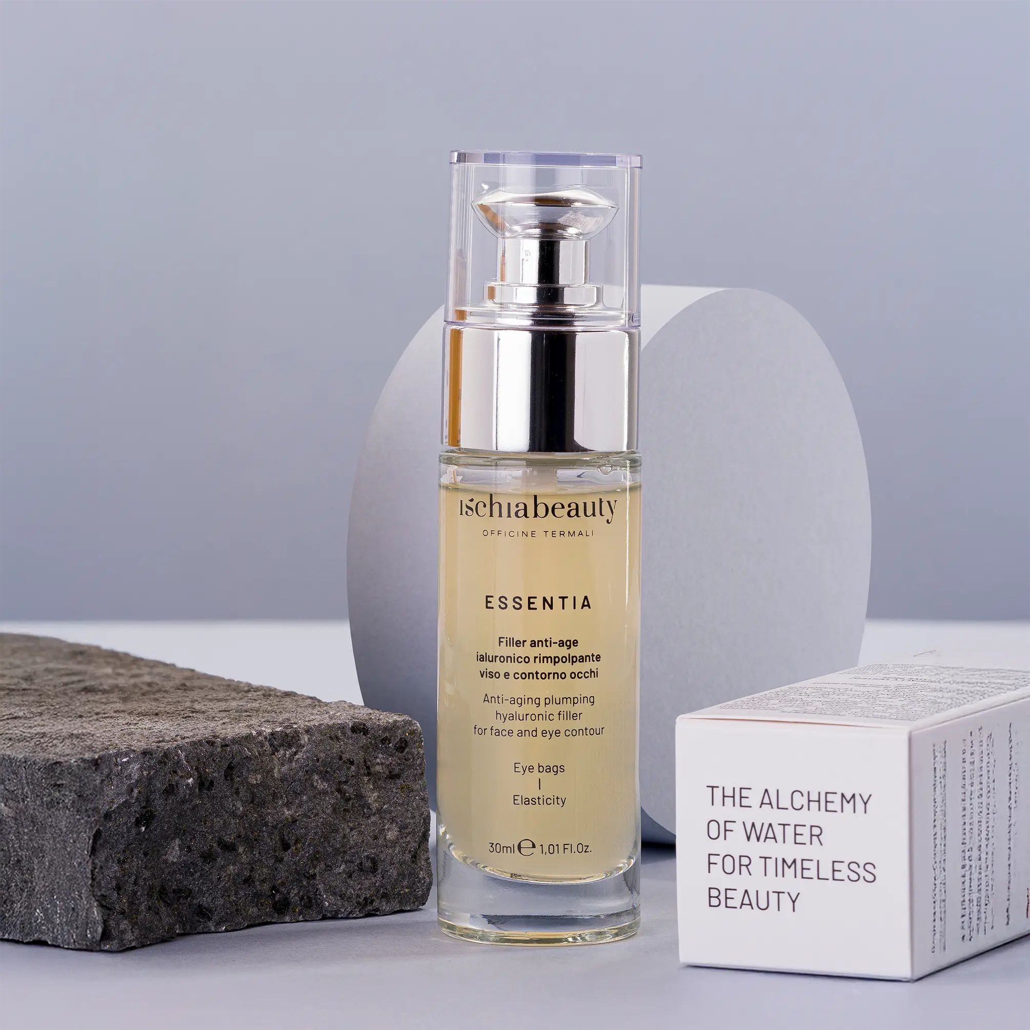 Glasflasche mit silberner Pumpe. Aufschrift: ischiabeauty, ESSENTIA, Filler anti-age, Augenringe, Elastizität. Karton mit Text.