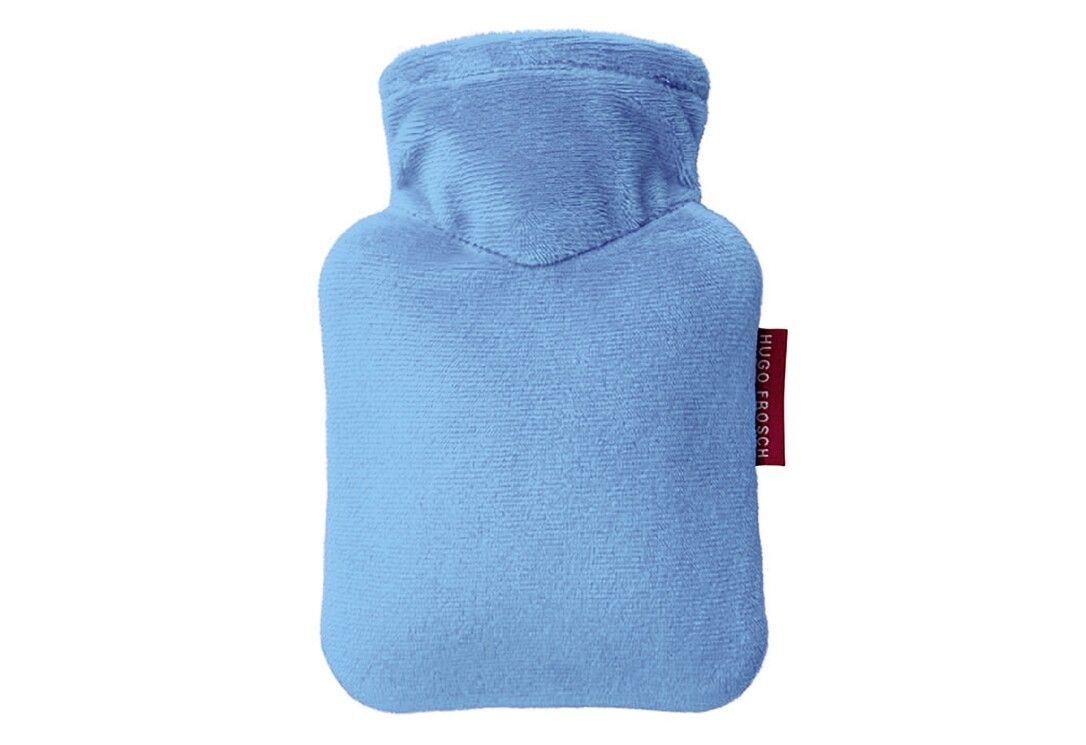 Hellblaue Wärmflasche mit Stoffbezug. Rotes Etikett mit Schriftzug.