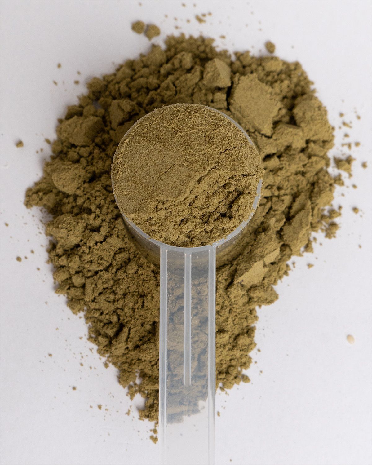 Ein Messlöffel mit grünem Hanfprotein Pulver, umgeben von Pulver.