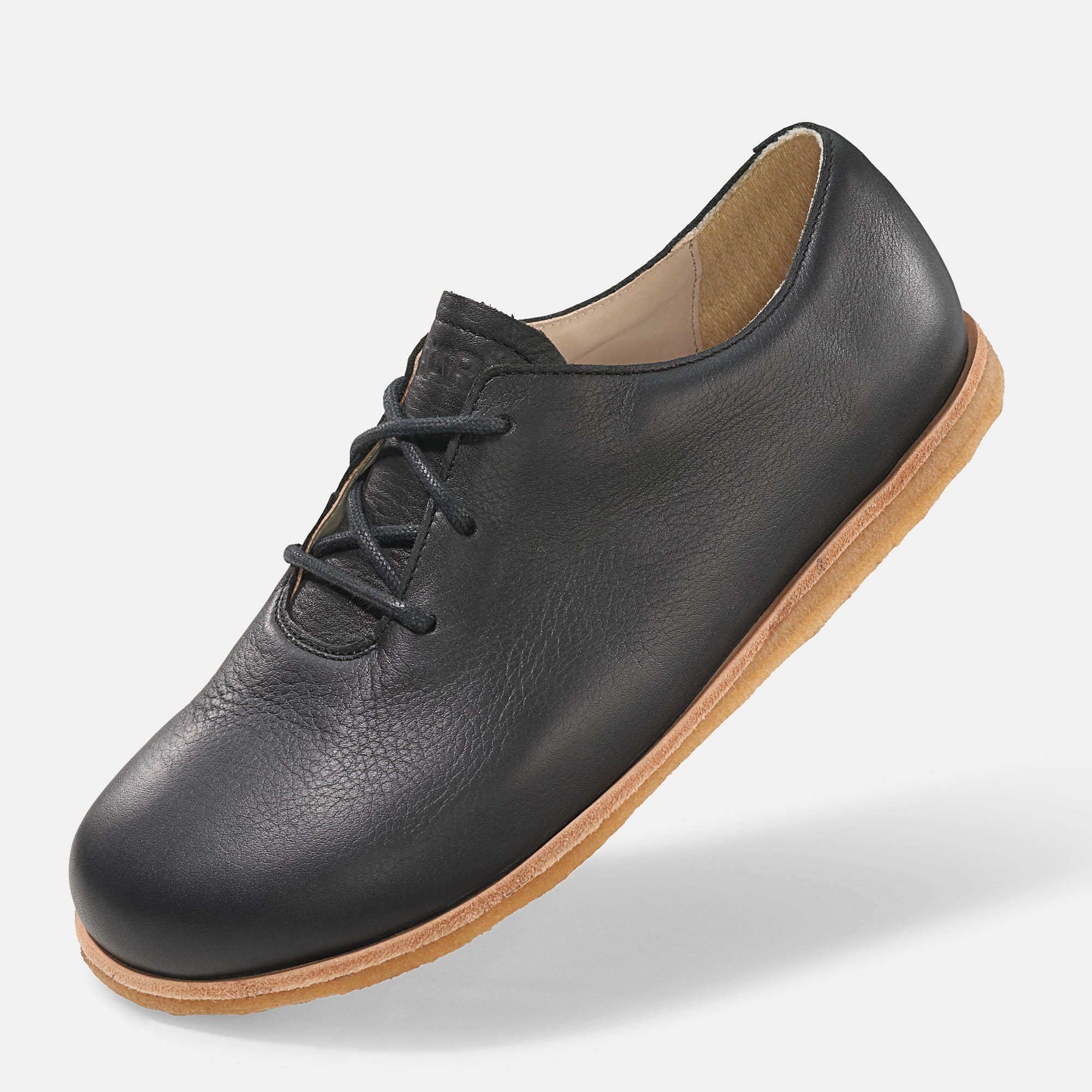 Schwarzer Lederschnürschuh mit heller Sohle. Schuh von der Seite, leicht schräg. Schnürsenkel sichtbar.