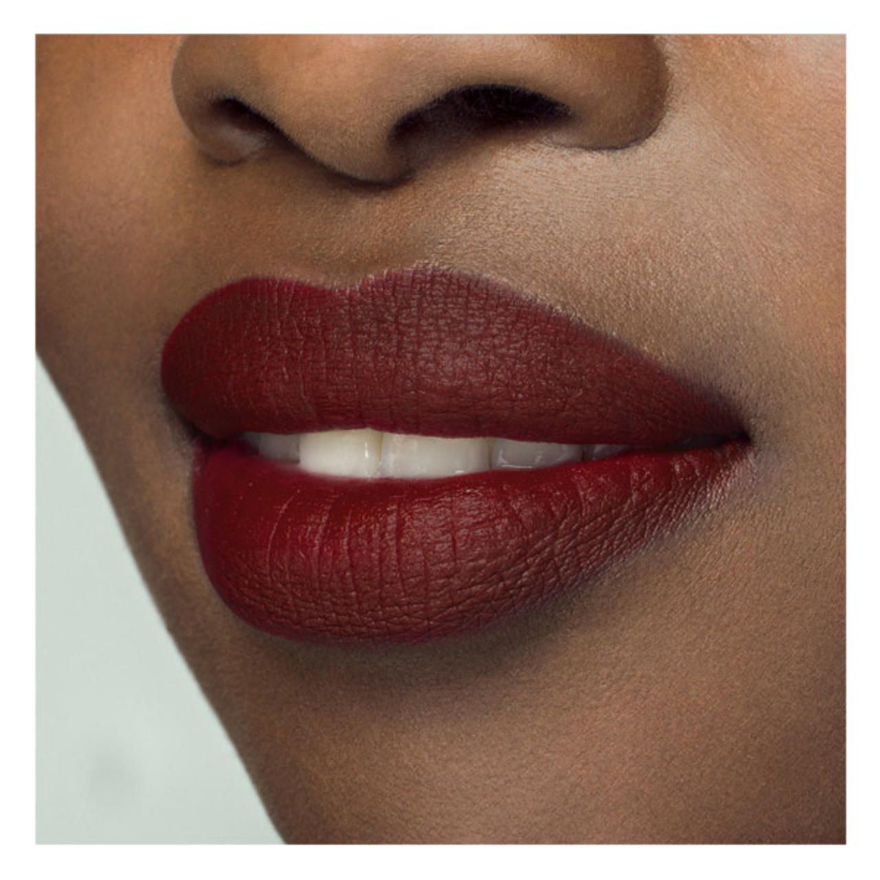 Nahaufnahme von Lippen, die mit burgunderrotem Lippenstift bemalt sind. Die Lippen sind voll und haben eine matte Oberfläche.
