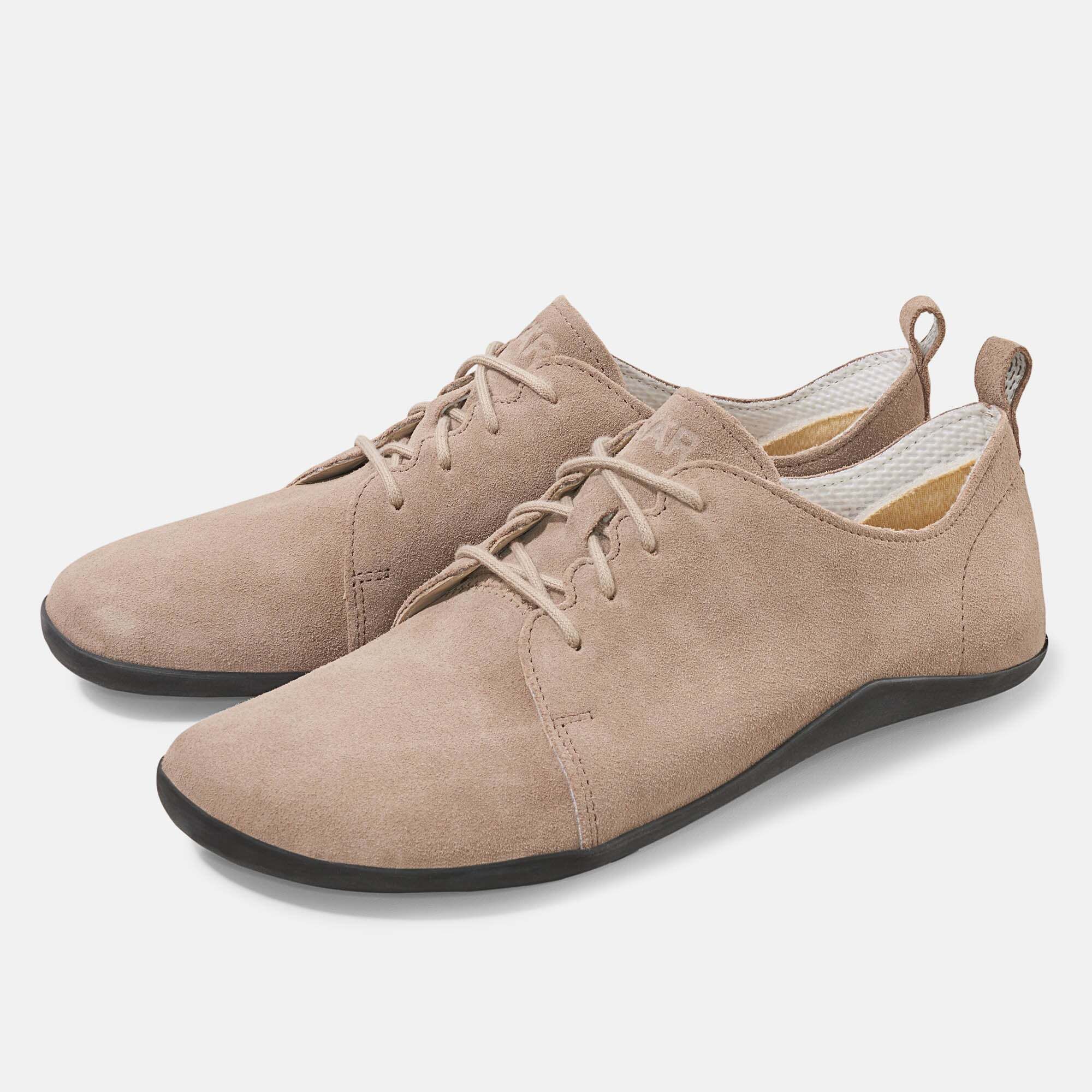 Zwei beigefarbene Schnürschuhe. Obermaterial aus Wildleder, schwarze Sohle. Schnürsenkel. Auf der Zunge steht BÄR.