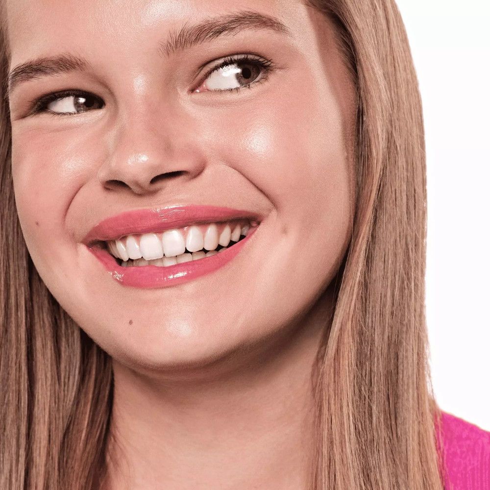 Porträt einer lächelnden Frau. Sie trägt rosa Lipgloss. Lange blonde Haare. Nahaufnahme.