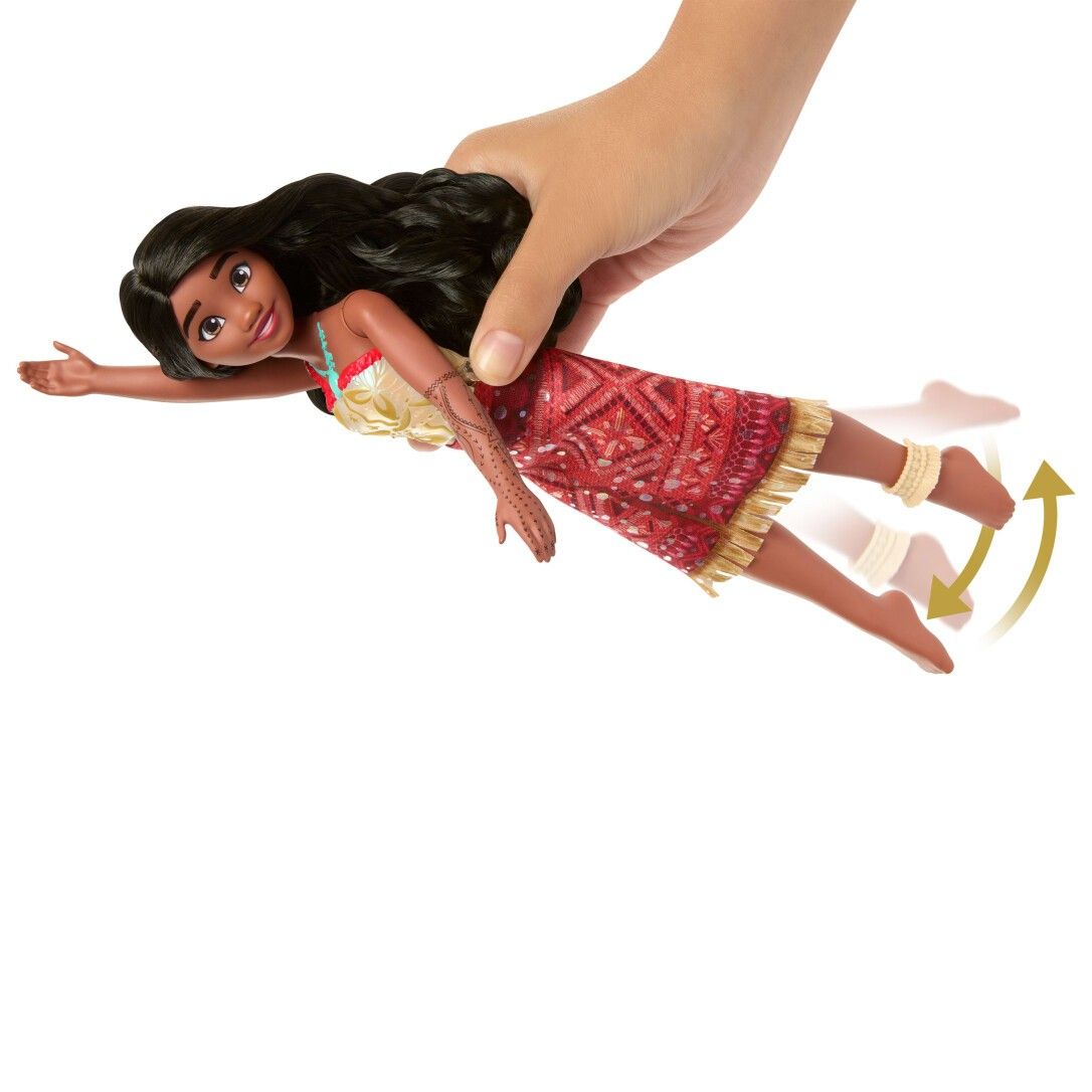 Puppe mit langen schwarzen Haaren, rotem Kleid und Armbändern. Eine Hand hält die Puppe.