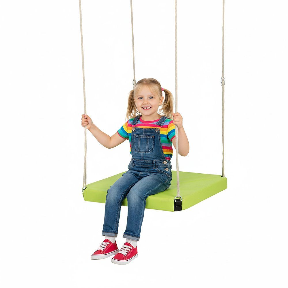 Kind sitzt auf grüner Plattformschaukel. Seile zur Aufhängung. Kind trägt Latzhose und Shirt. Weißer Hintergrund.