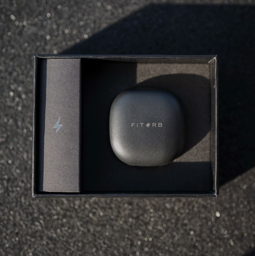 Schwarze Box mit Ladestation und Ladekabel. Marke: FITORB.