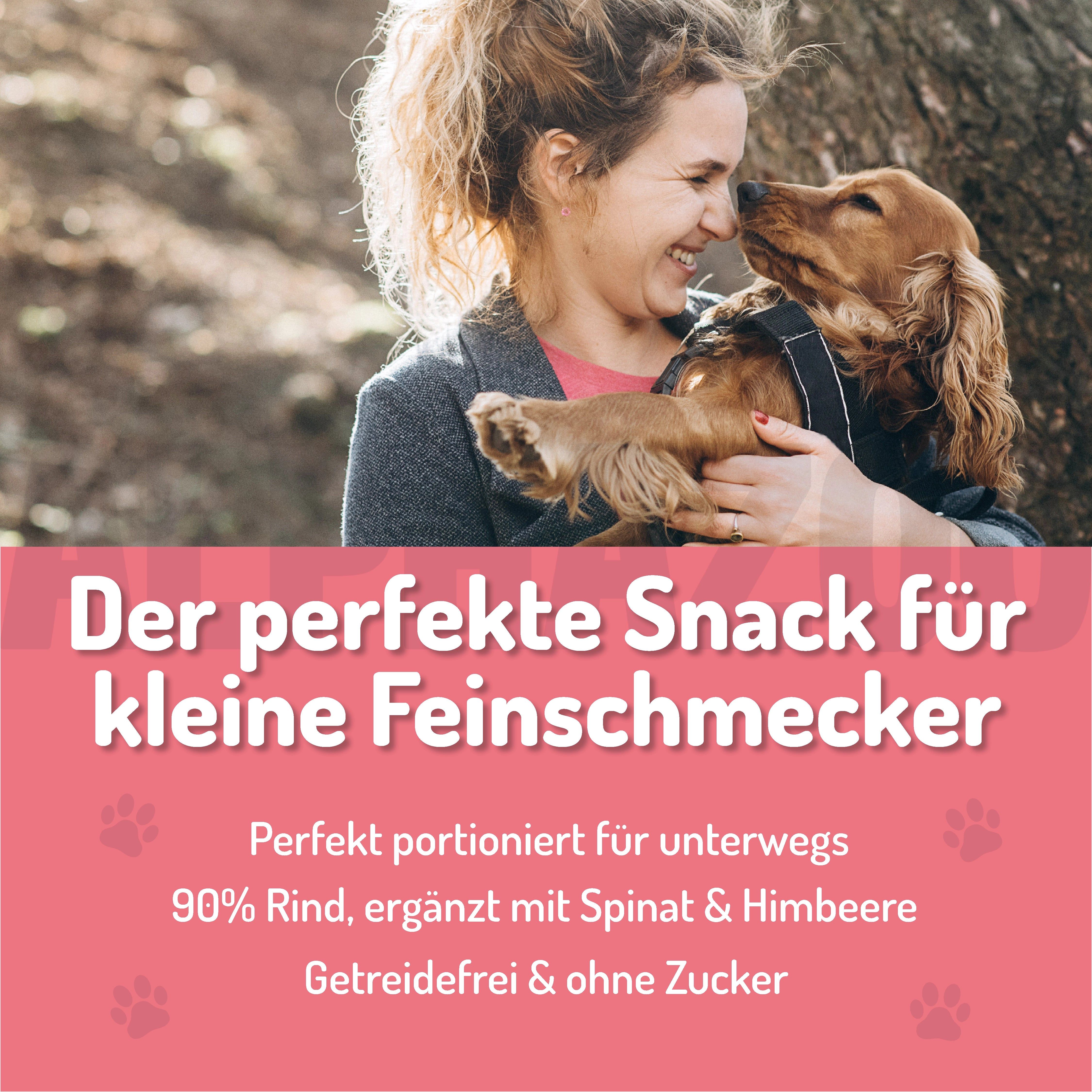 Frau umarmt einen Hund. Text: Der perfekte Snack für kleine Feinschmecker. 90% Rind, ergänzt mit Spinat & Himbeere. Getreidefrei & ohne Zucker.