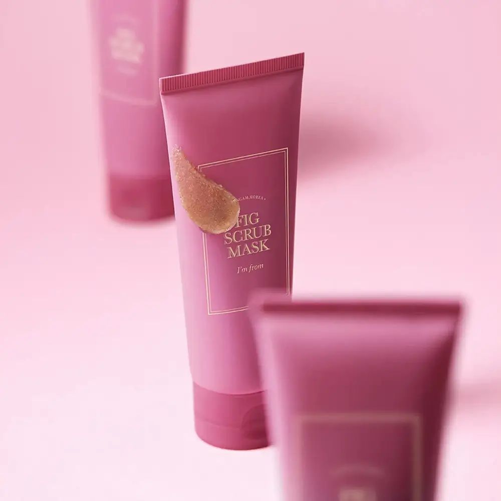 Drei rosa Tuben mit goldfarbenem Aufdruck. Aufschrift: FIG SCRUB MASK, I'M FROM. Produktverpackung.