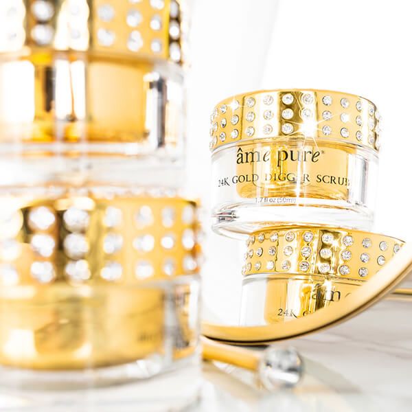 Meerdere potjes met goudkleurige scrub. Opschrift: âme pure 24K GOLD DIGGER SCRUB. Gouden spatel.