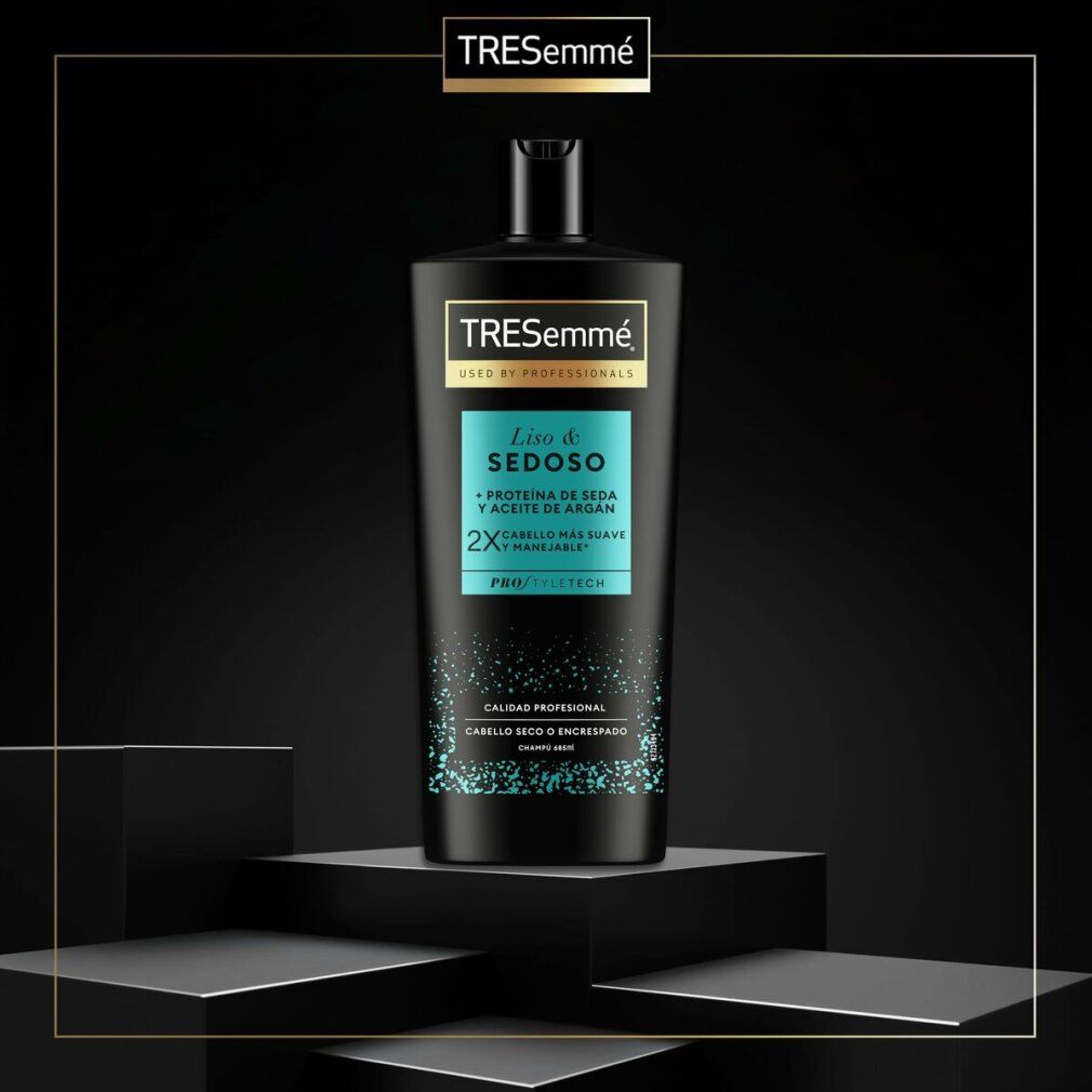 Schwarze TRESemmé Shampoo-Flasche auf Podest. Aufschrift: Liso & Sedoso, Protein de Seda y Aceite de Argán. Für trockenes oder krauses Haar.