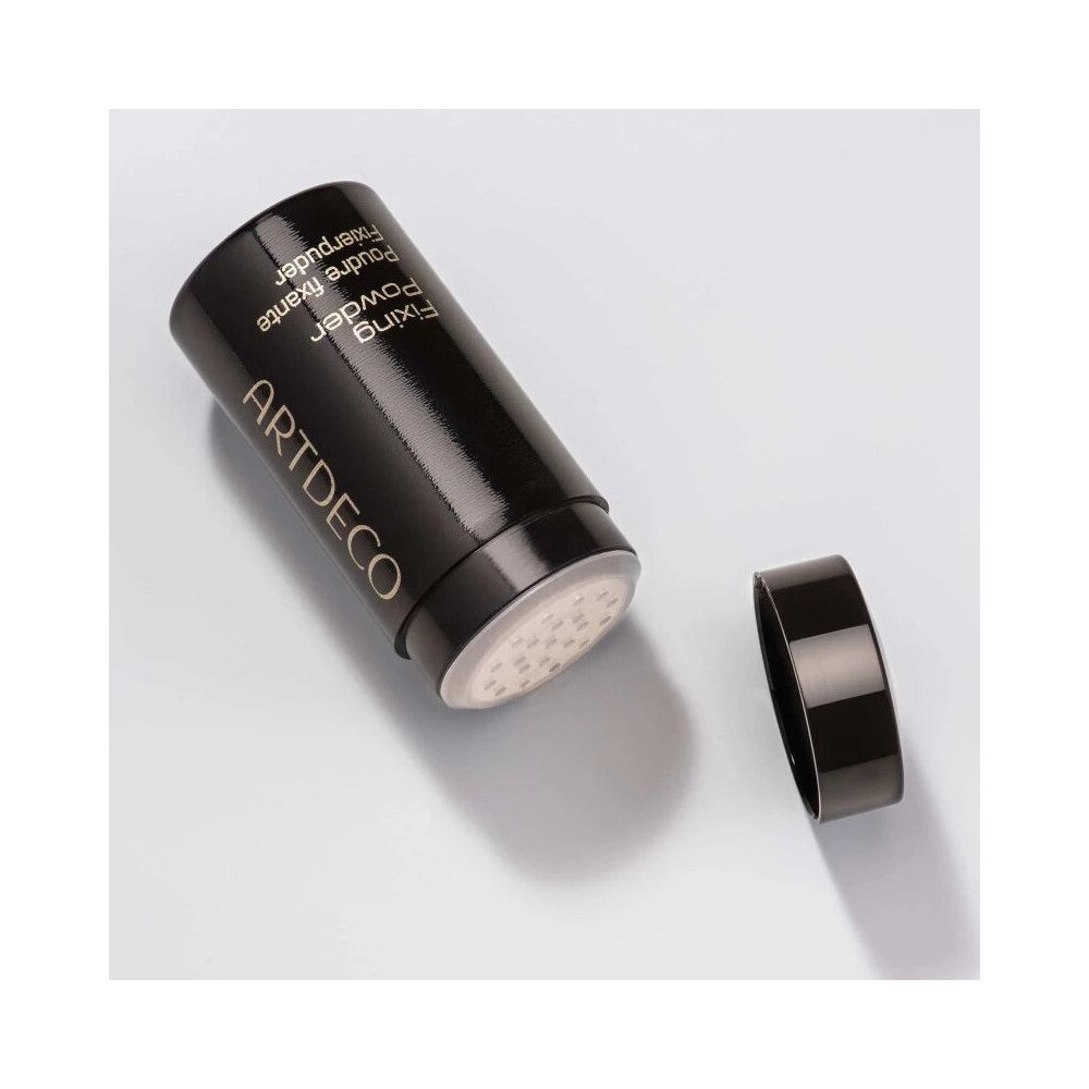 Schwarze Dose mit Deckel, geöffnet. Sichtbar: Öffnung mit Löchern. Aufschrift: ARTDECO, Fixing Powder, Poudre fixante, Fixierpuder.