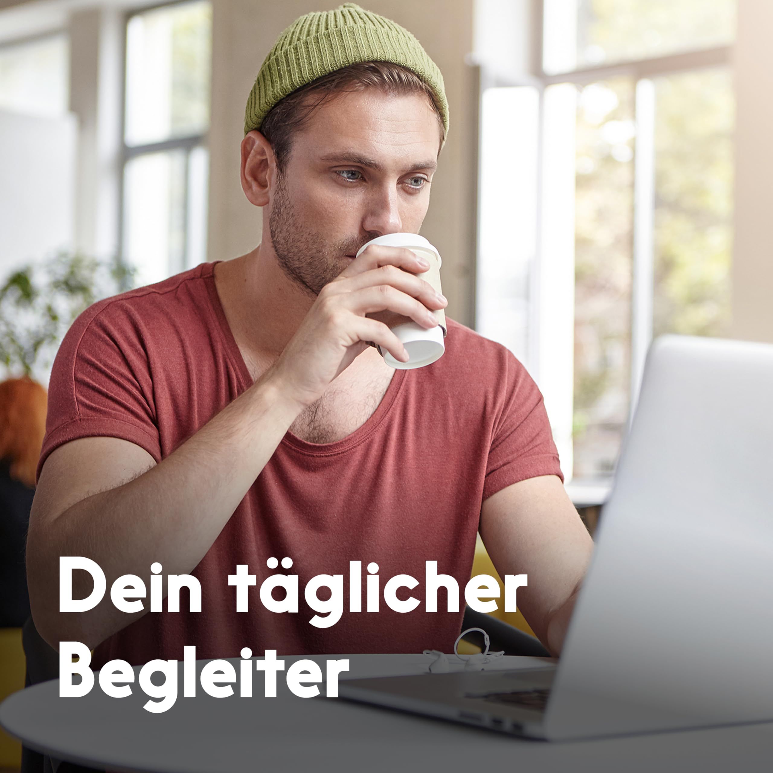 Mann trinkt aus einem Pappbecher, sitzt vor einem Laptop. Text: Dein täglicher Begleiter.