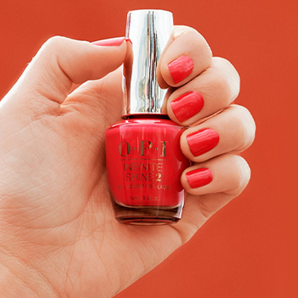 Hand hält Nagellackflasche. Nägel mit rotem Lack. OPI Infinite Shine 2 Schriftzug.