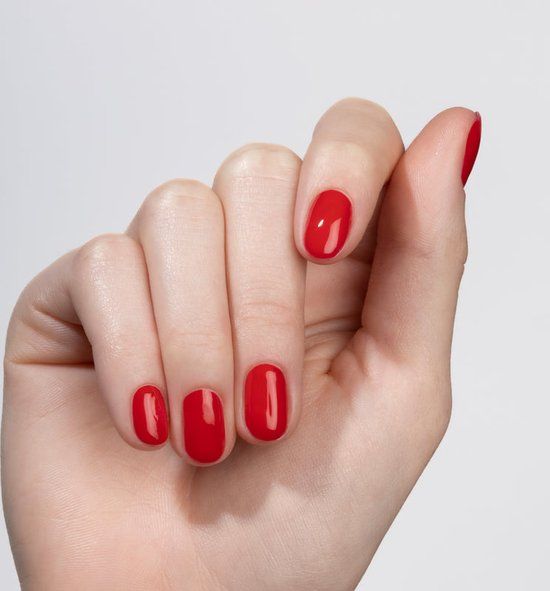 Hand mit lackierten Nägeln. Farbe: N22 Red Velvet. Glänzendes Finish. Alle Nägel lackiert.