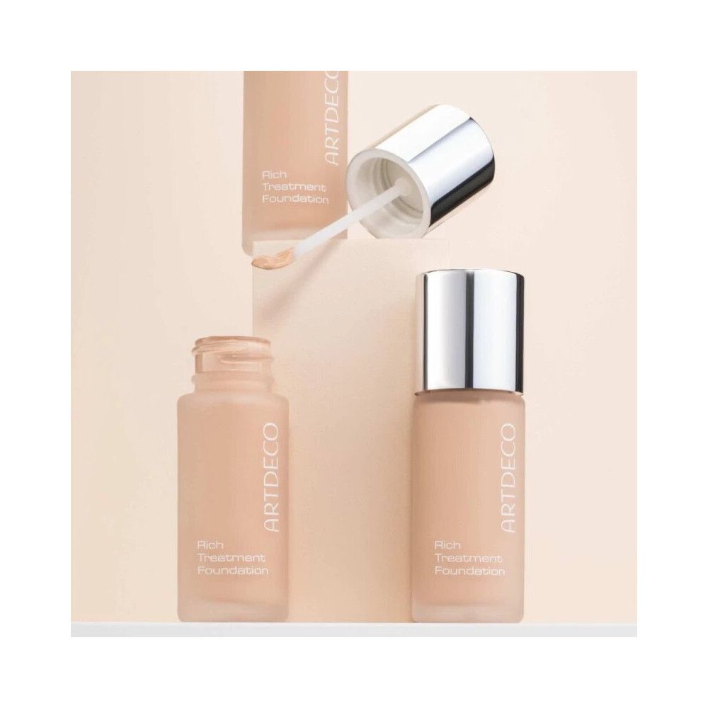 Artdeco Rich Treatment Foundation. Flasche mit silbernem Deckel und Applikator. Geöffnete Flasche und Produkt daneben.