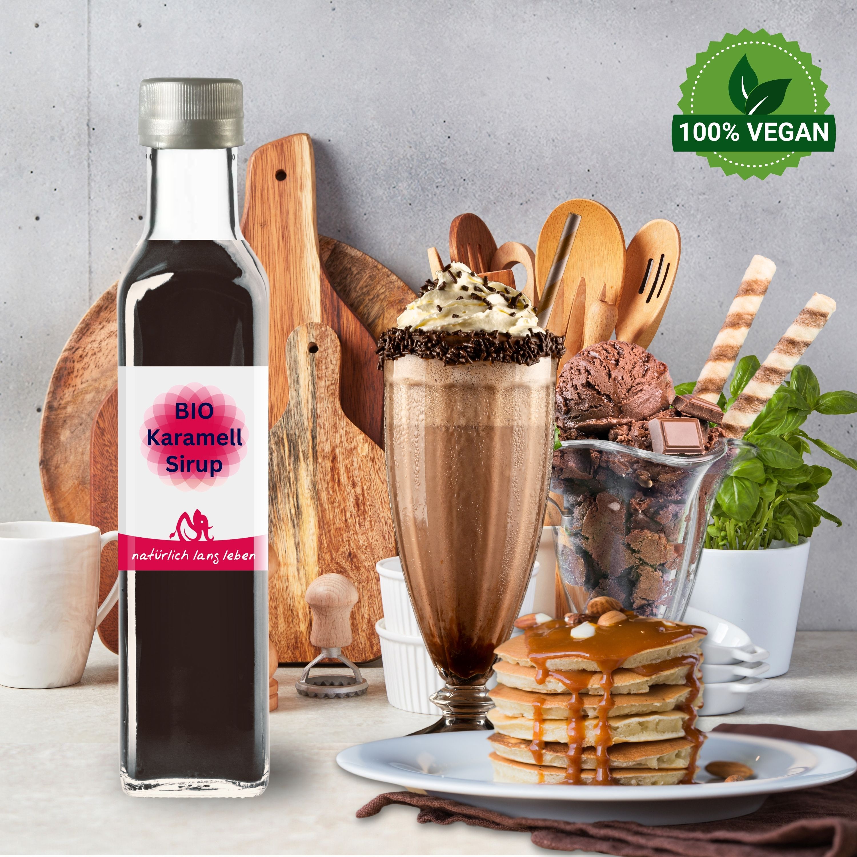 Glasflasche mit braunem Inhalt und Etikett. Aufschrift: BIO Karamell Sirup. Auf einem Tisch mit Dessert.