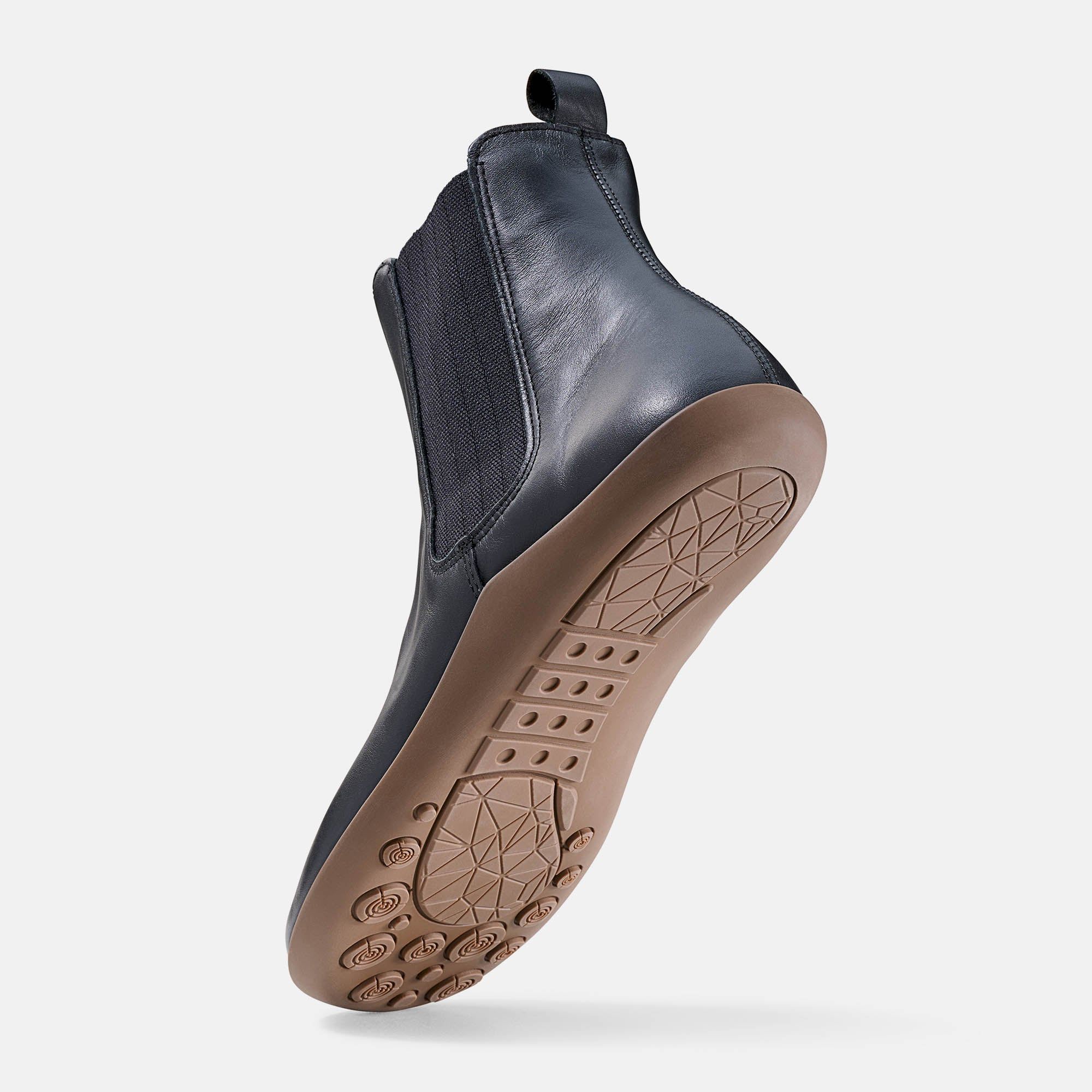 Schwarze Stiefelette, flache Sohle, breite Passform. Sohle mit Profil. Schuhansicht von unten.