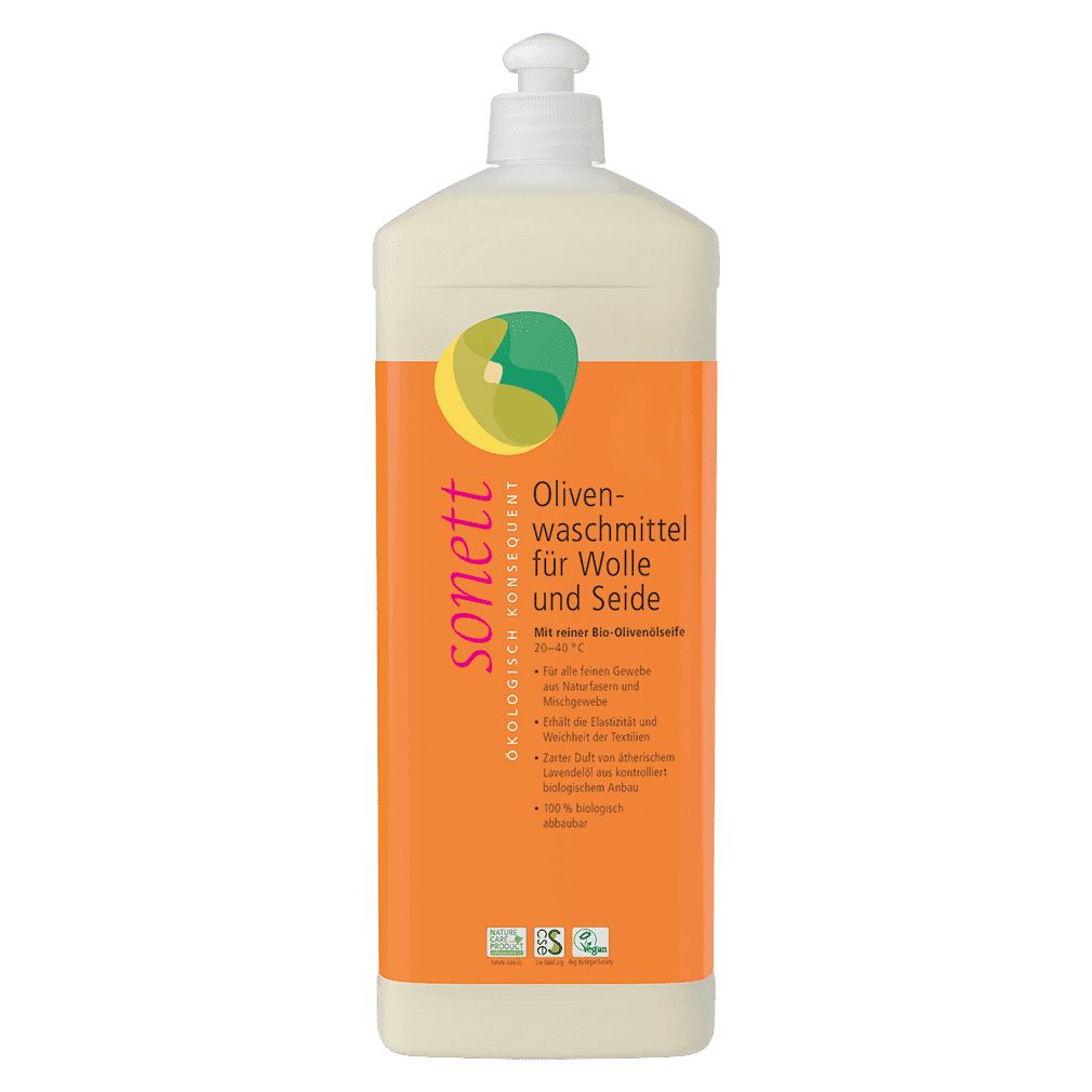 Flasche mit Olivenwaschmittel für Wolle und Seide. Orangefarbener Hintergrund mit Produktinformationen und Logo. Weißer Dosierkopf.