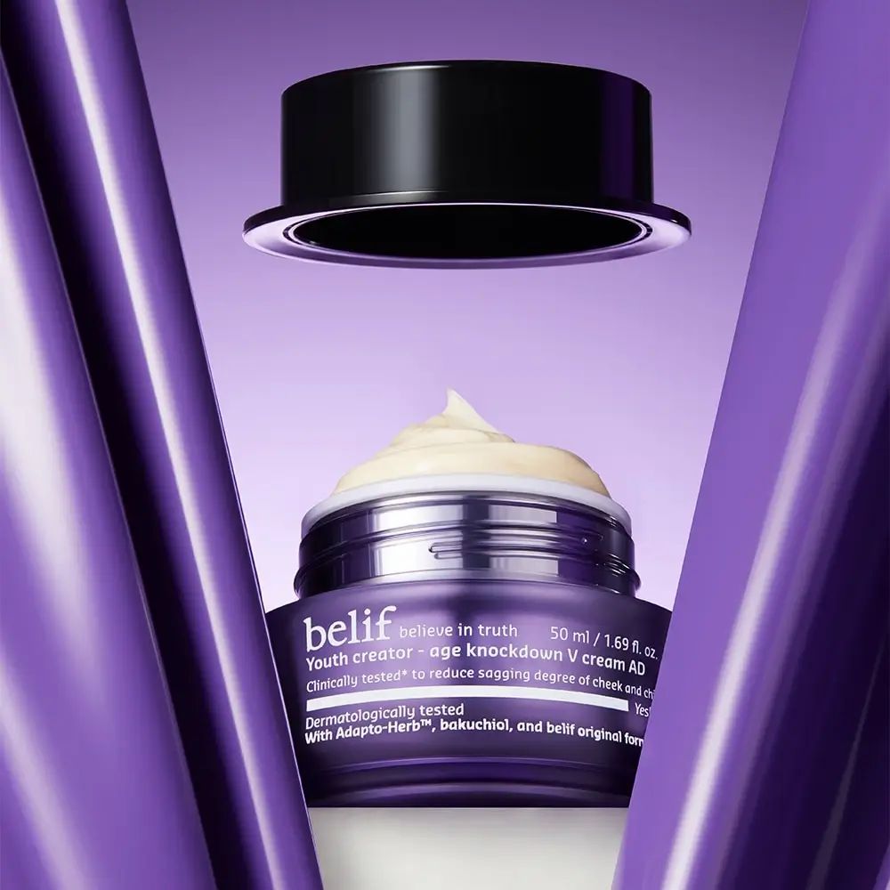 Geöffneter lila Tiegel mit Creme. Schwarzer Deckel darüber. Aufschrift: belif, Youth creator - age knockdown V cream AD. Text: Klinisch getestet.