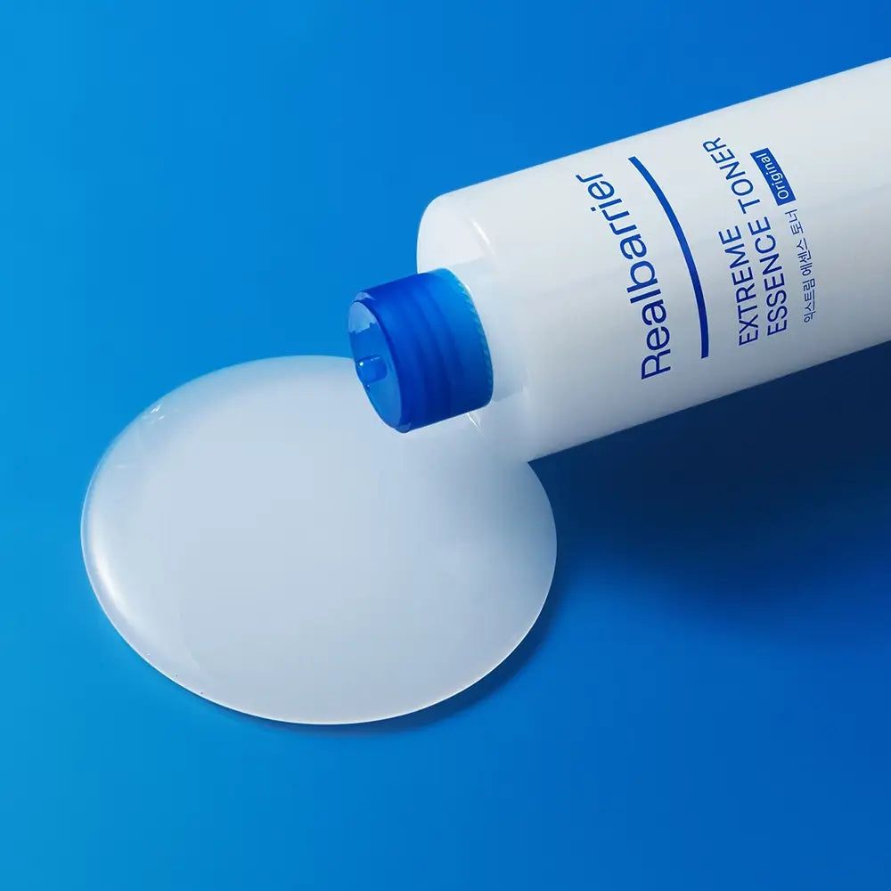 Weiße Flasche mit blauem Deckel, Flüssigkeit daneben. Produktname und Schriftzug sichtbar.