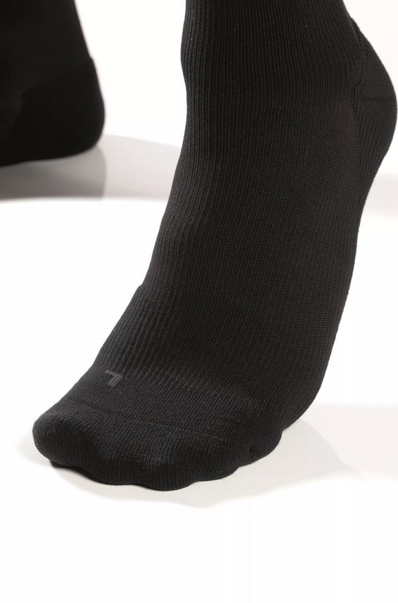 Nahaufnahme eines schwarzen Kompressionsstrumpfes. Geripptes Material, Fußbereich.