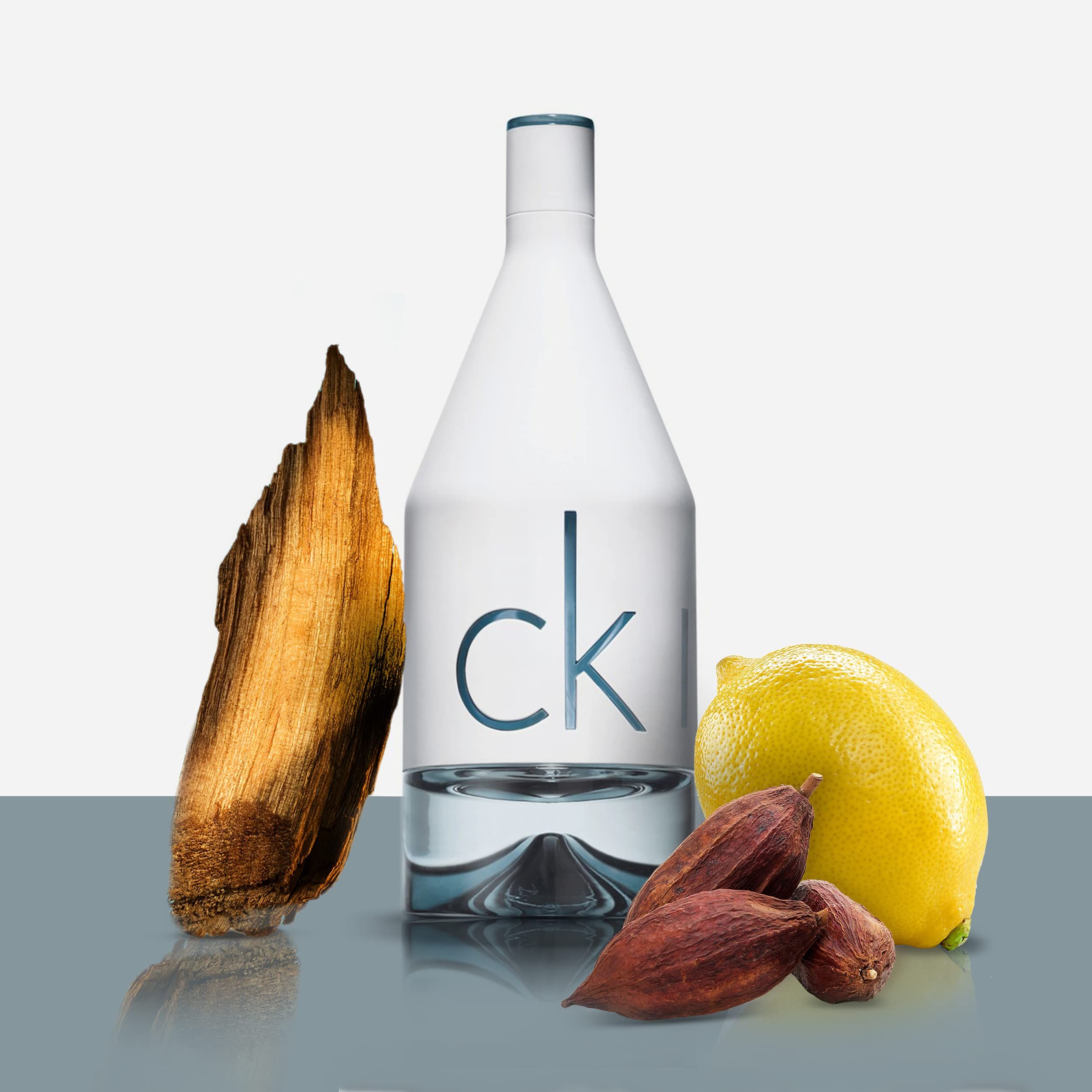 Eine weiße Flasche mit der Aufschrift "ck" und Zutaten: Holz, Zitrone und Kakaobohnen.