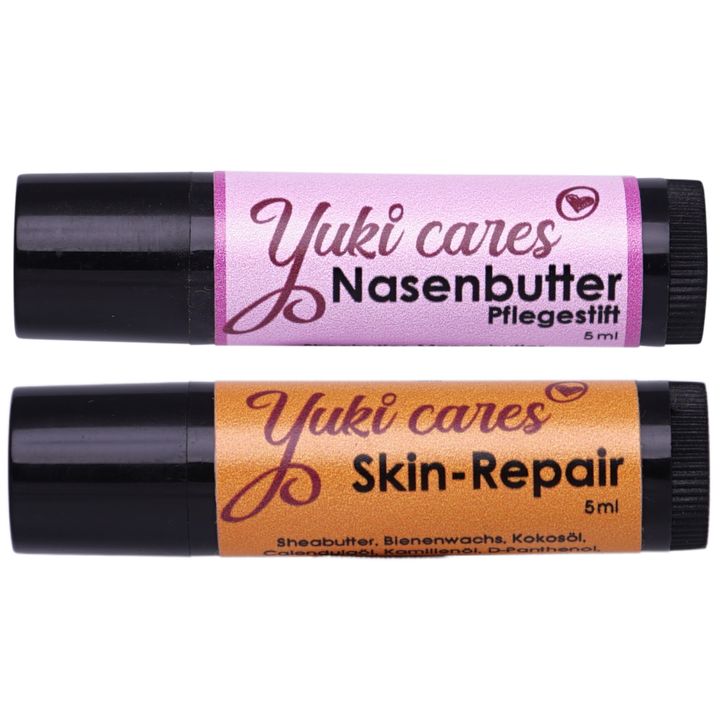 Zwei Stifte von Yuki cares. Einer ist Nasenbutter, der andere Skin-Repair. Beide haben schwarze Hüllen und 5ml Inhalt.