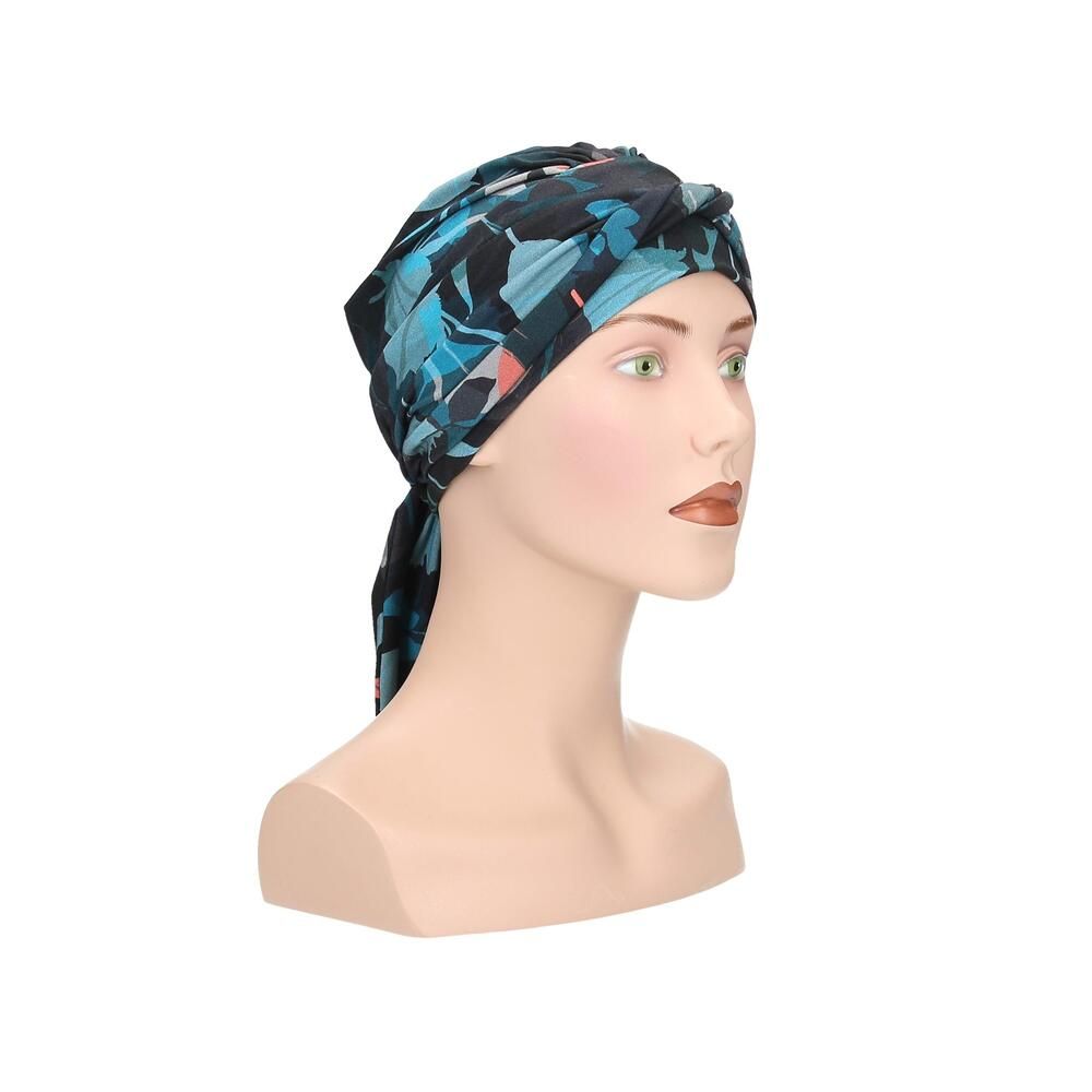 Turban Letti, floral bedruckt, auf einer Büste. Farben: Schwarz, Türkis, Rosa. Stoff mit Falten. Dreiviertelansicht.