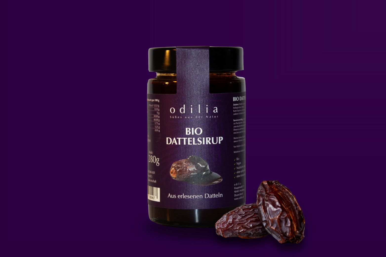 Flasche mit Bio-Dattelsirup von Odilia, daneben zwei Khudri-Datteln.