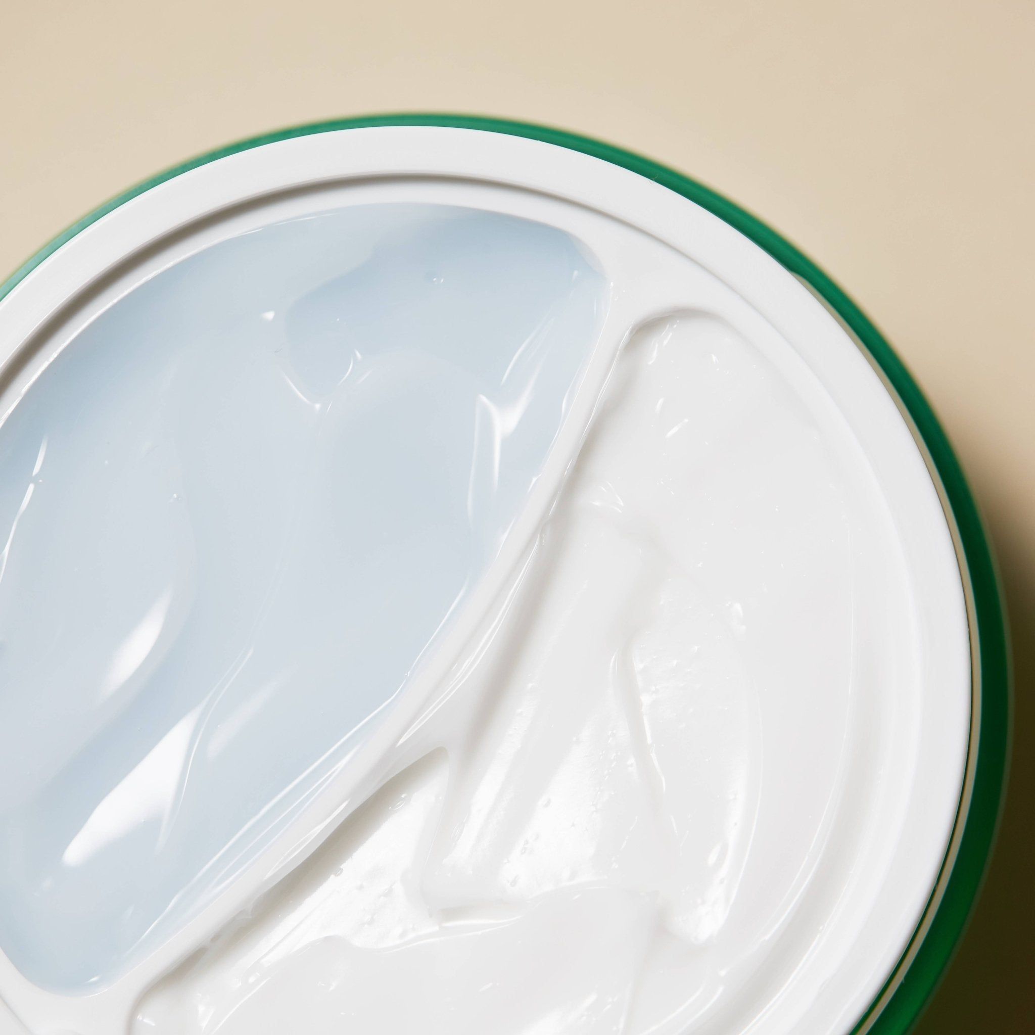 Nahaufnahme der Creme-Oberfläche. Zwei getrennte Bereiche: eine weiße Creme und eine transparente Gel-Textur.