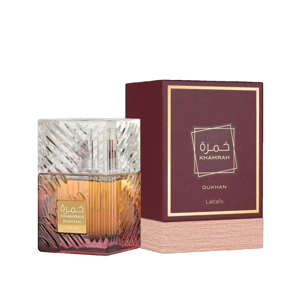 Parfümflakon und Verpackung. Flakon mit quadratischem Design, goldfarbenem Inhalt und transparentem Deckel. Verpackung in Burgunderrot.