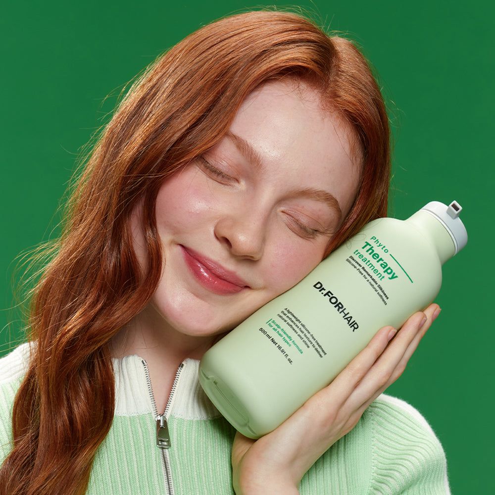 Frau mit roten Haaren hält eine Flasche Dr. FORHAIR Phyto Therapy Treatment Balsam.