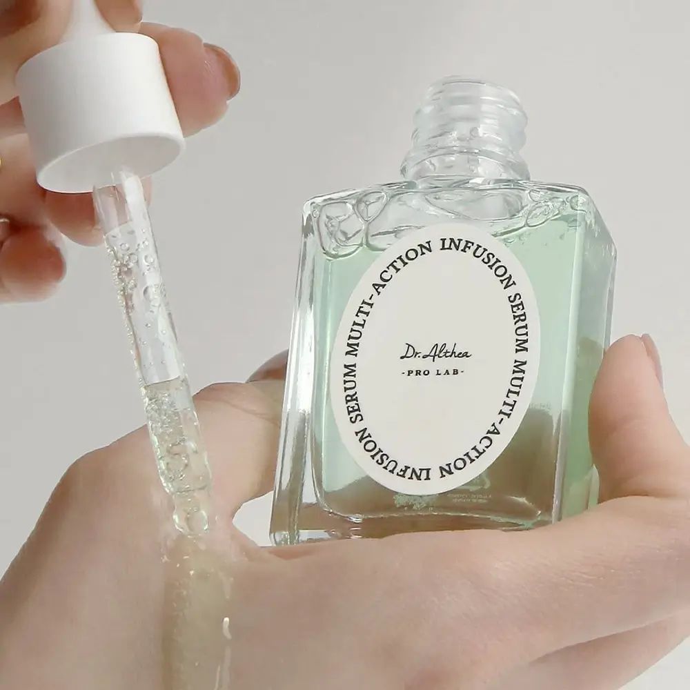 Hand hält Serumflasche und Pipette. Serum wird auf die Hand getropft. Flasche mit Etikett.