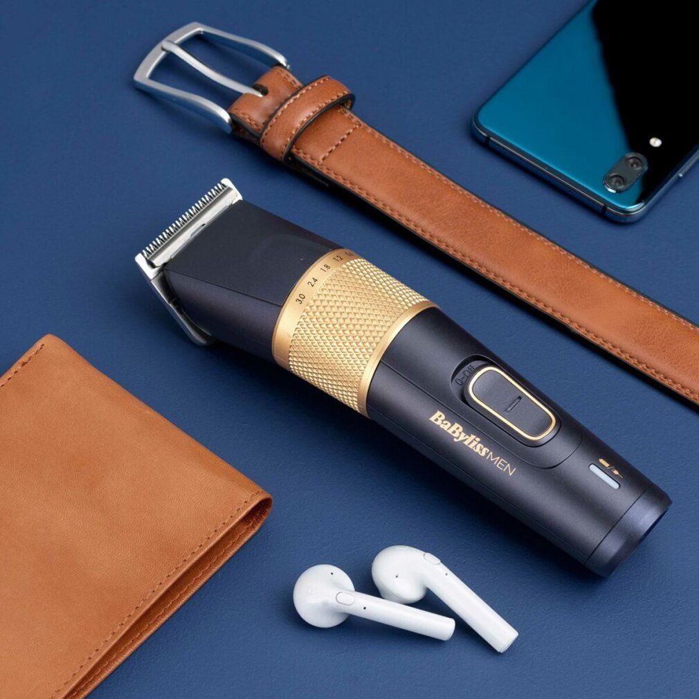 Haarschneider, Ledergeldbörse, Gürtel, Smartphone und Kopfhörer auf blauem Hintergrund.