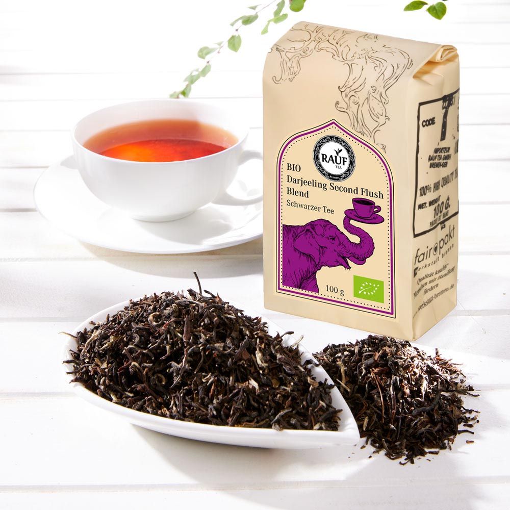 Rauf Tee Darjeeling Second Flush Bio, Beutel neben Tasse Tee und losem Tee. Bio-Siegel sichtbar.