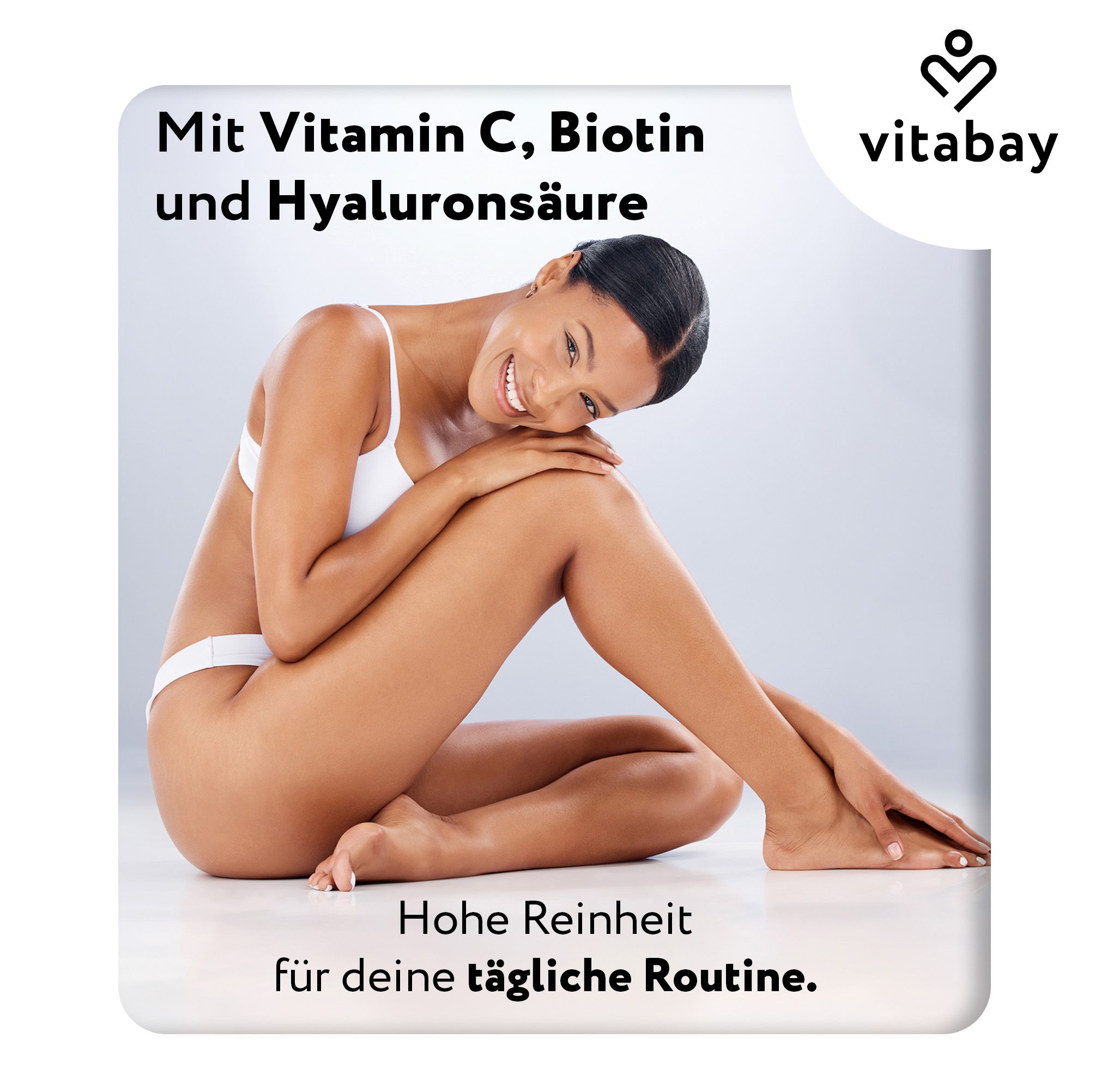 Junge Frau sitzt, trägt weiße Unterwäsche. Text: Mit Vitamin C, Biotin und Hyaluronsäure. Hohe Reinheit für deine tägliche Routine.