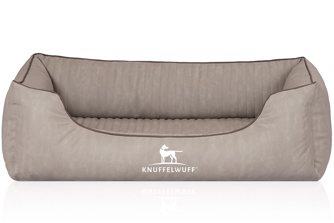 Beiges orthopädisches Hundebett mit brauner Umrandung. Logo: Hund und Schriftzug Knuffelwuff. Rechteckige Form mit erhöhten Seiten.