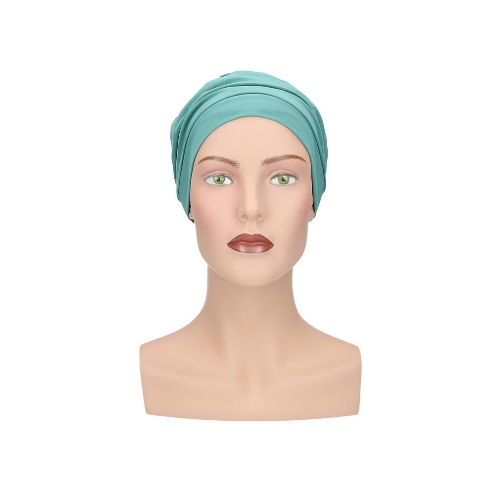 Türkisfarbener Turban auf einer Schaufensterpuppe. Frontansicht. Glatter Stoff, gerüschte Details.