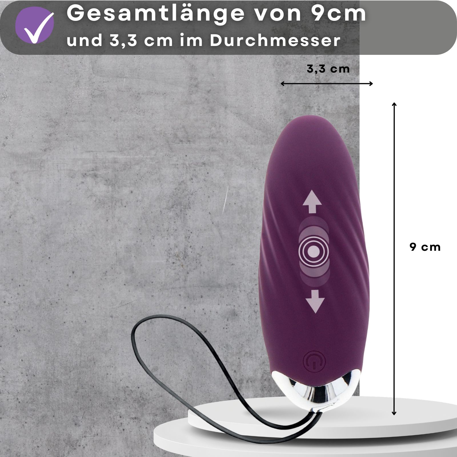 Lila Ei-Vibrator, 9 cm lang, 3,3 cm Durchmesser. Auf weißem Podest. Grauer Hintergrund.