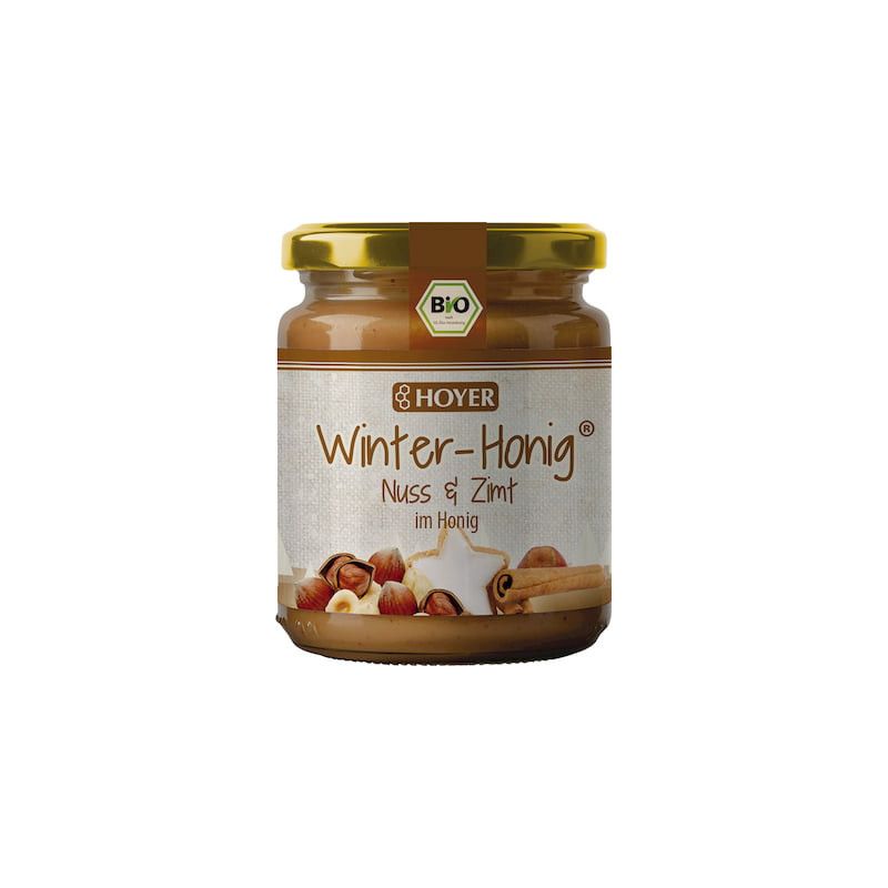 Glas mit Honig. Aufschrift: Winter-Honig, Nuss & Zimt. Bio-Siegel. Haselnüsse, Zimtstange und Stern auf Etikett.