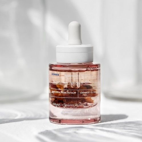 Gesichtsöl-Flakon mit Pipette. Rosa Flüssigkeit mit Blütenblättern. Weißer Deckel mit Aufschrift KORRES.