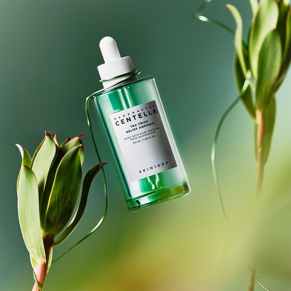 Grüne Glasflasche mit Pipette, umgeben von grünen Pflanzen und Draht. Schwebend in der Luft.