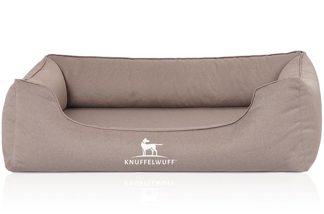 Orthopädisches Hundebett in Beige. Rechteckige Form mit erhöhtem Rand. Logo mit Hund und Schriftzug.