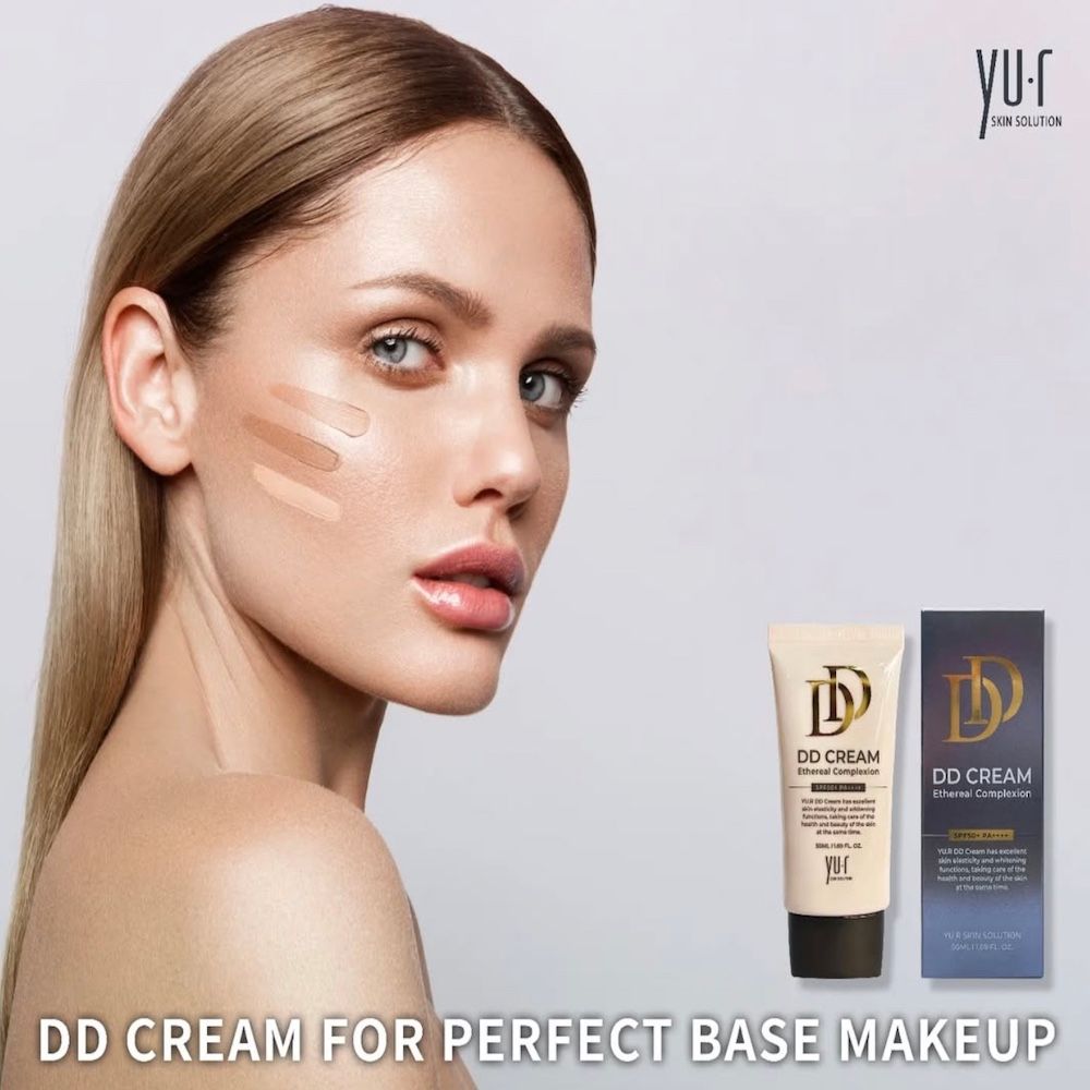 Frau mit Farbtupfern im Gesicht. Daneben Tube und Schachtel. Aufschrift: DD CREAM. Marke: Yu.r Skin Solution. Text: Perfect Base Makeup.