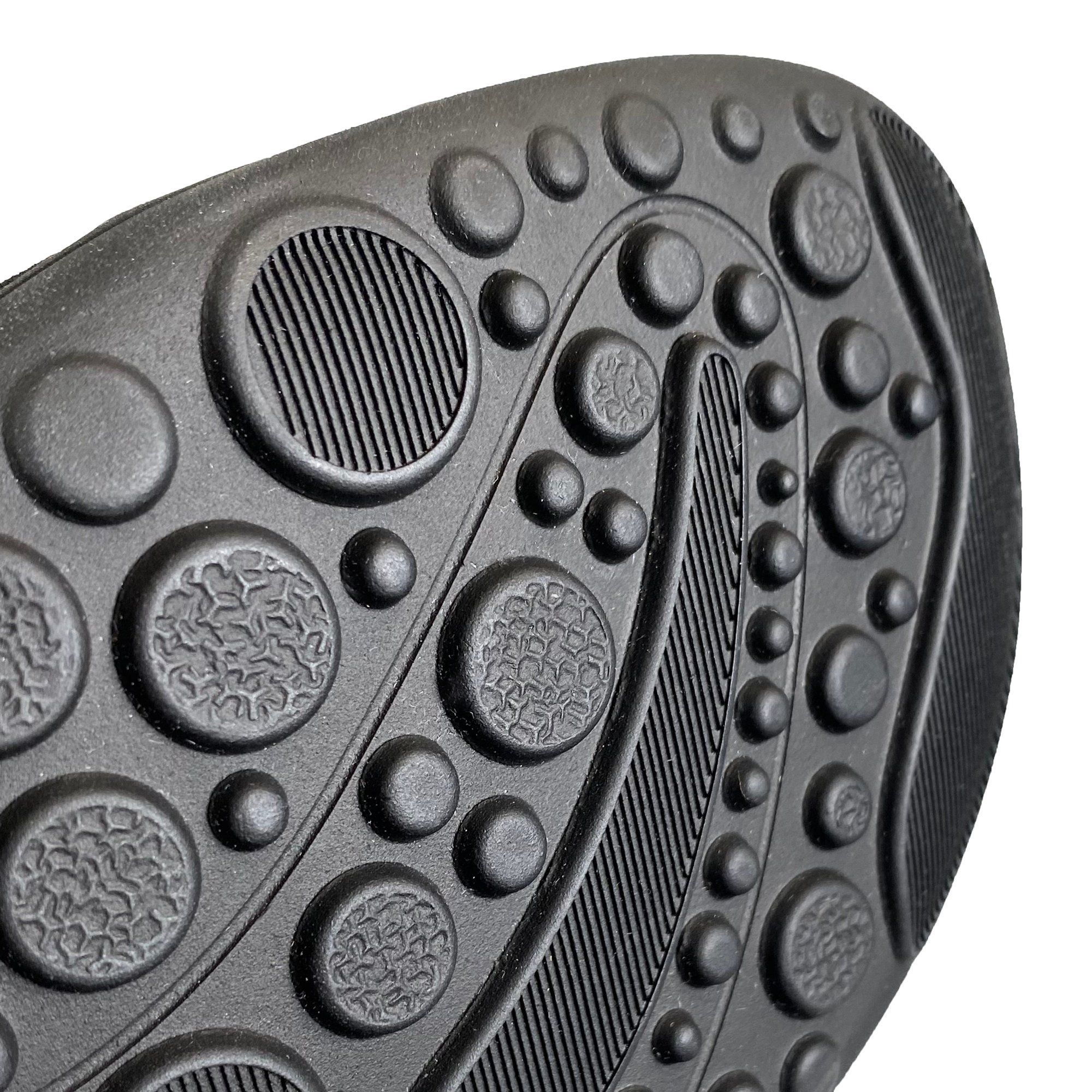 Nahaufnahme der schwarzen Sohle der Stiefelette. Profilierte Oberfläche mit Kreisen und Rillen.