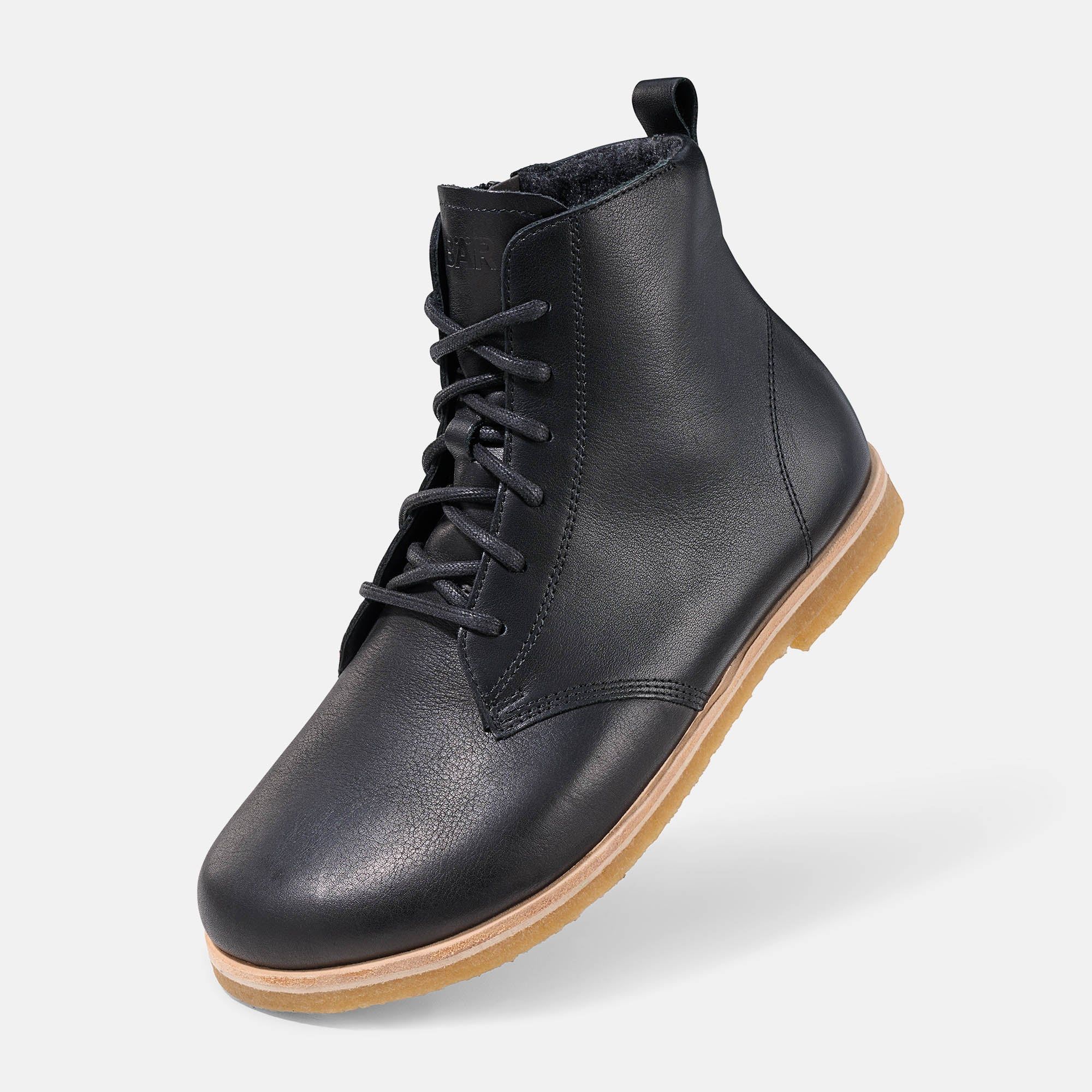 Schwarze Lederstiefelette, schräge Ansicht mit Schnürung und heller Gummisohle.